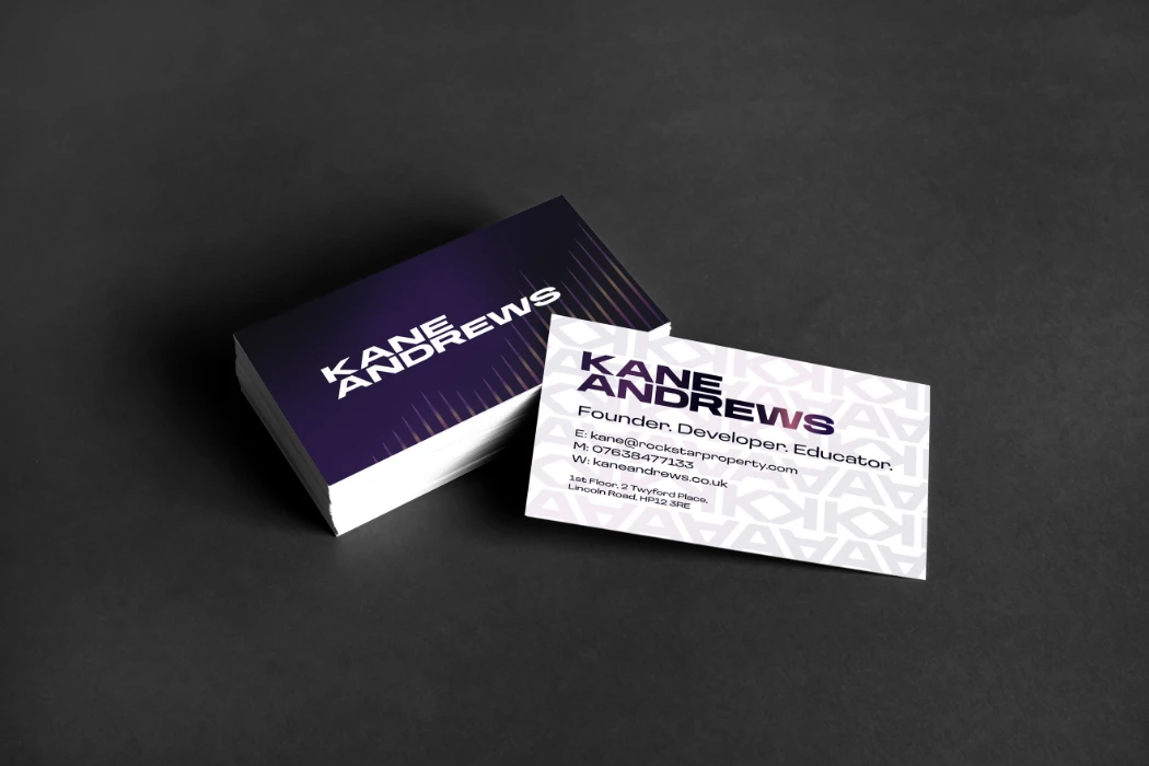 Purple and white business cards with the Kane Andrews branding on a dark grey background.