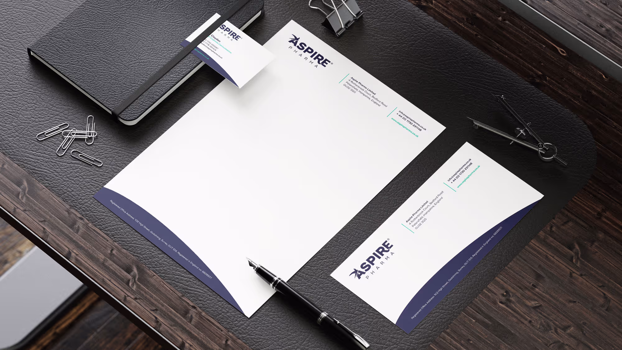 A stationary set with headed paper, and envelope and a business card with the Aspire Pharma branding.