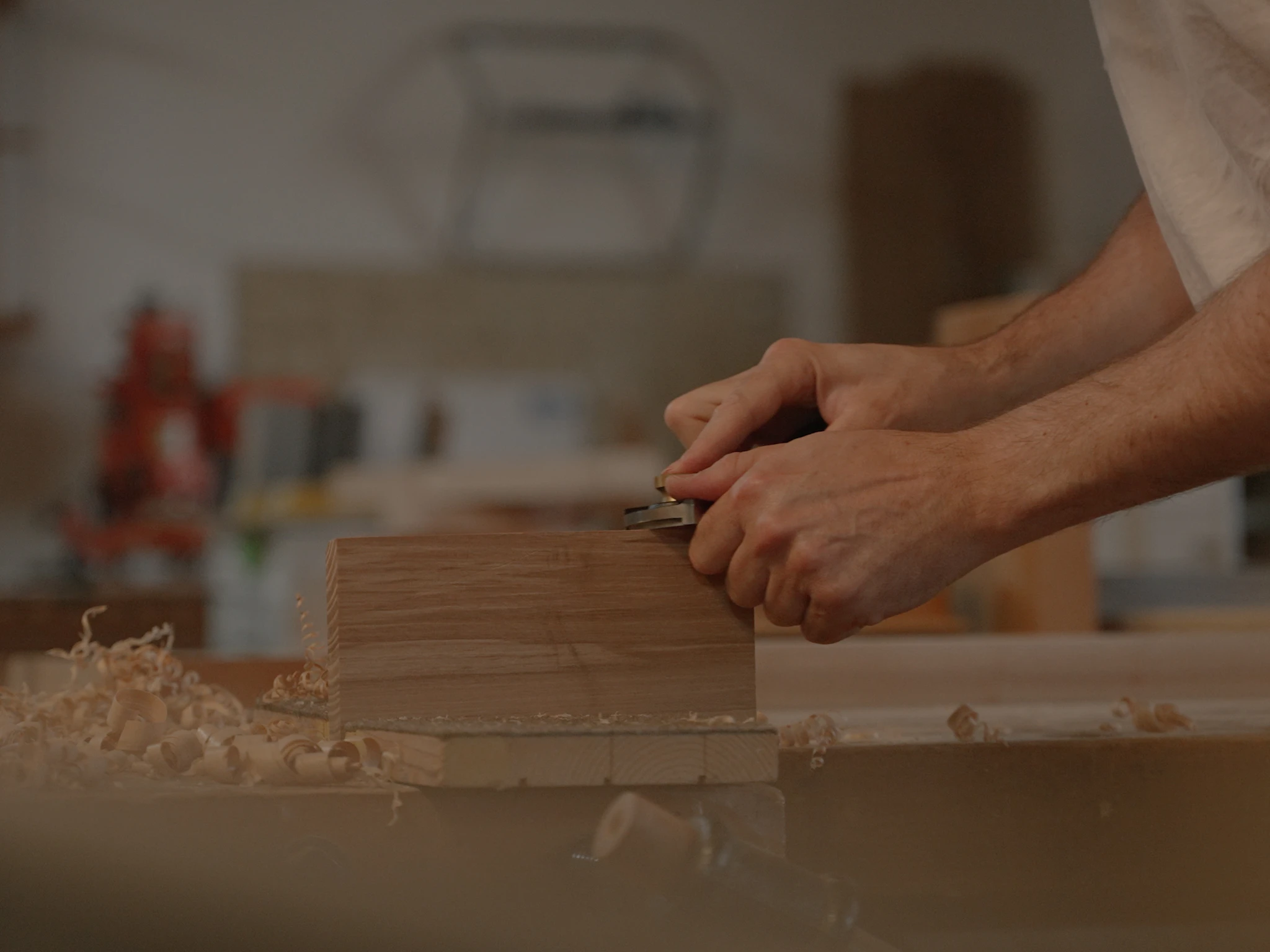 Handwerker beim Hobeln eines Holzblocks – steht symbolisch für präzise, traditionelle Handwerkskunst und die Vision von Instaltec