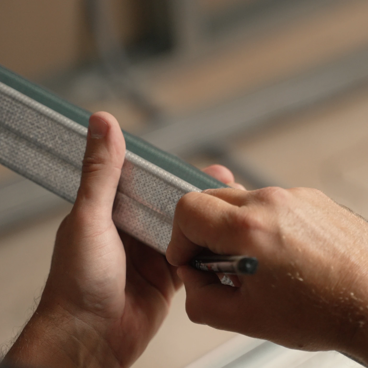 Hand markiert ein Metallprofil für den exakten Zuschnitt bei der Montage