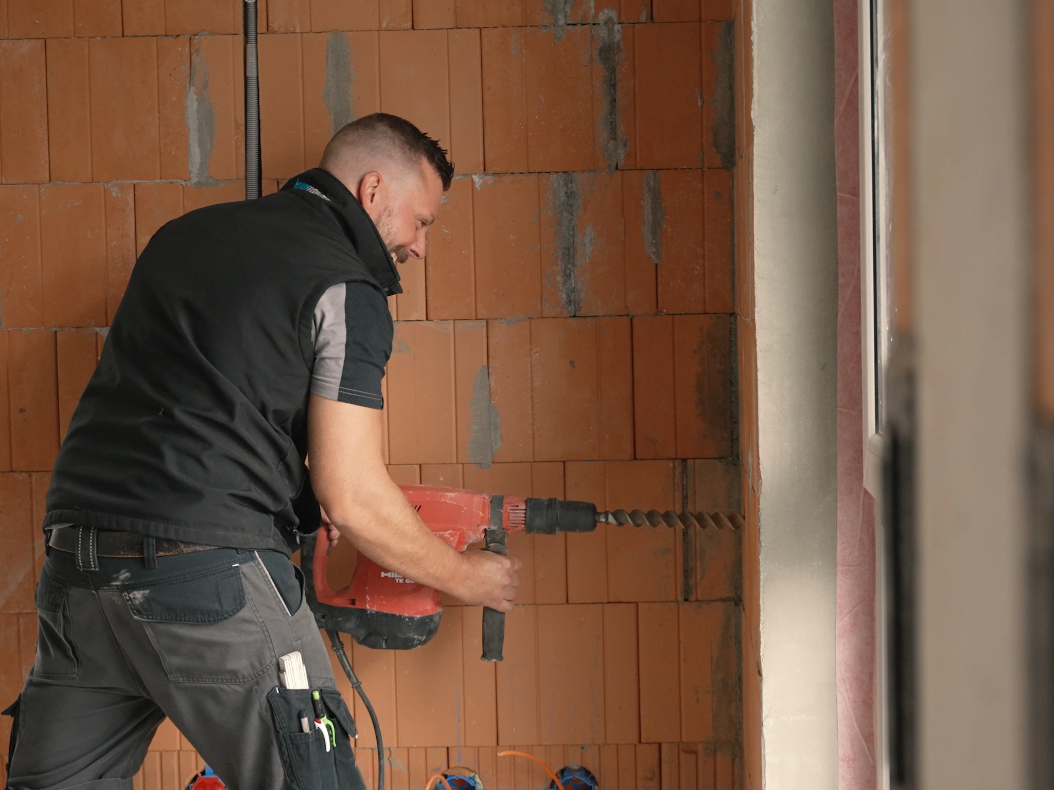 Handwerker bohrt mit großem Bohrhammer in eine Betonwand