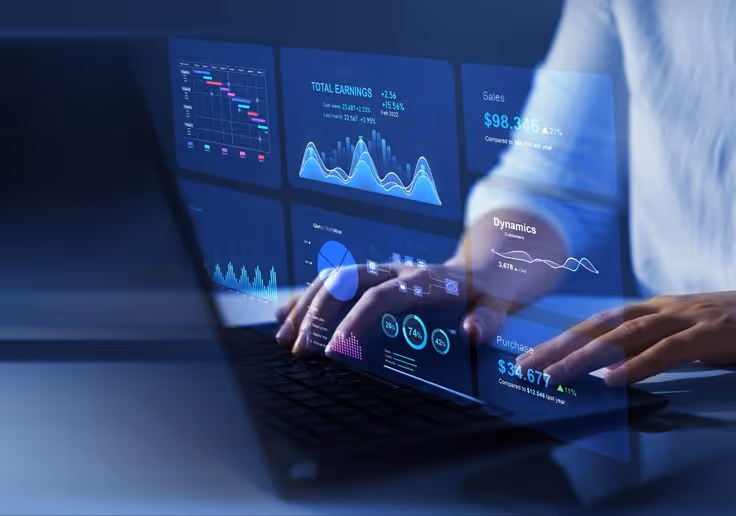 Person typing on a laptop with transparent digital financial charts and graphs projected above the keyboard.