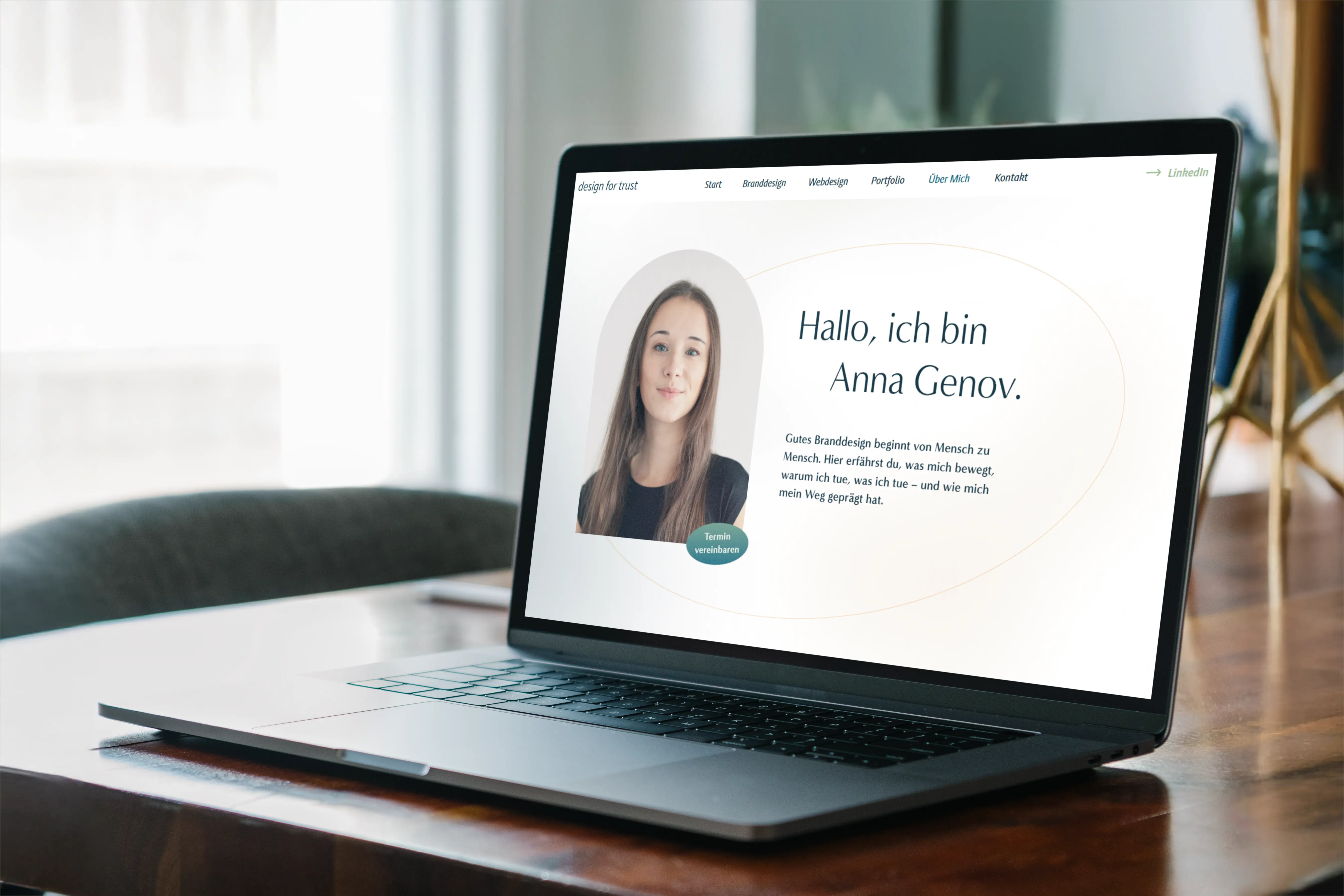 Laptop auf einem Holztisch zeigt eine Webseite mit einem Porträt von Anna Genov und einer Begrüßung.