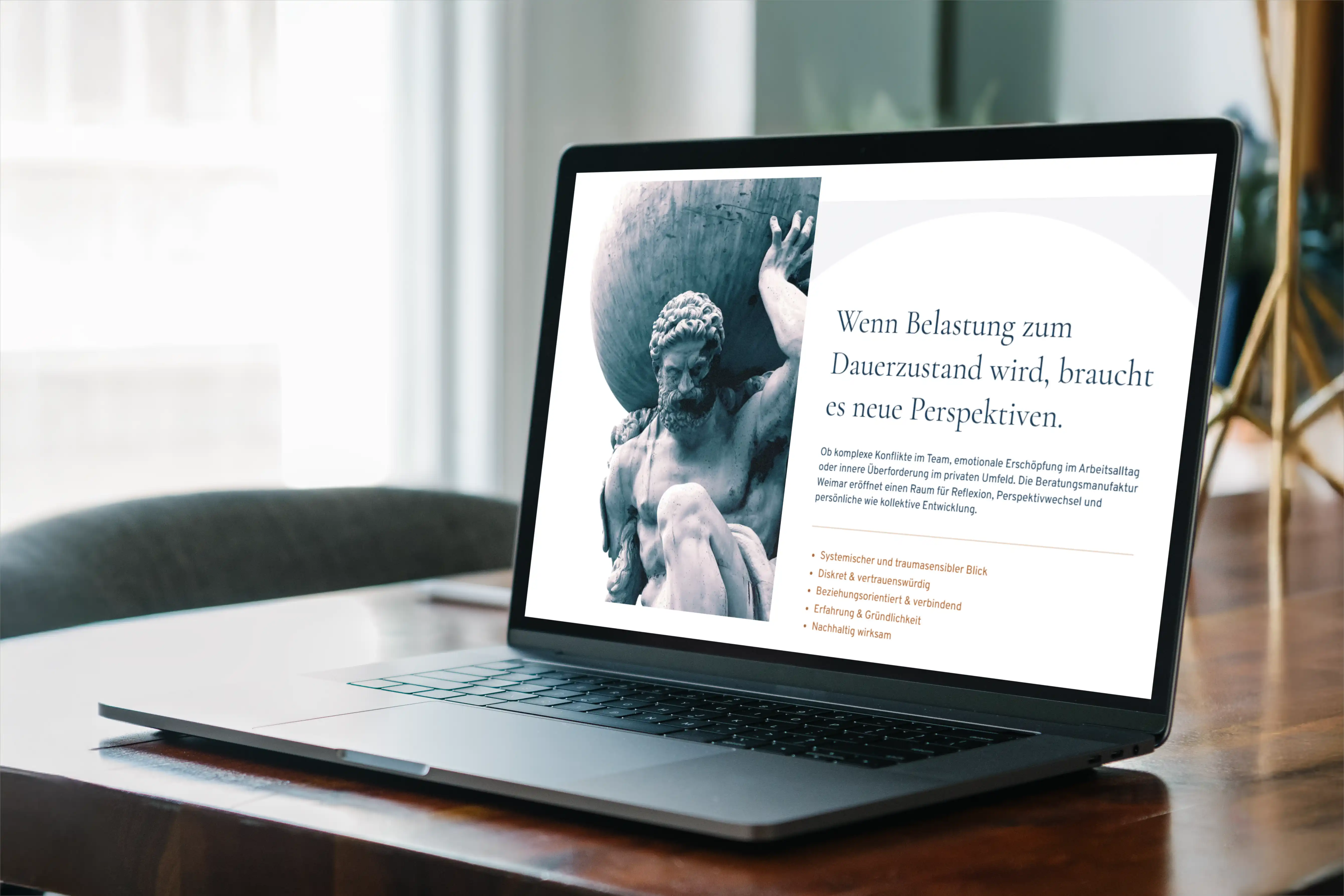 Laptop zeigt eine Webseite mit einer Statue, die einen großen Stein trägt, und Text über Belastung und neue Perspektiven.