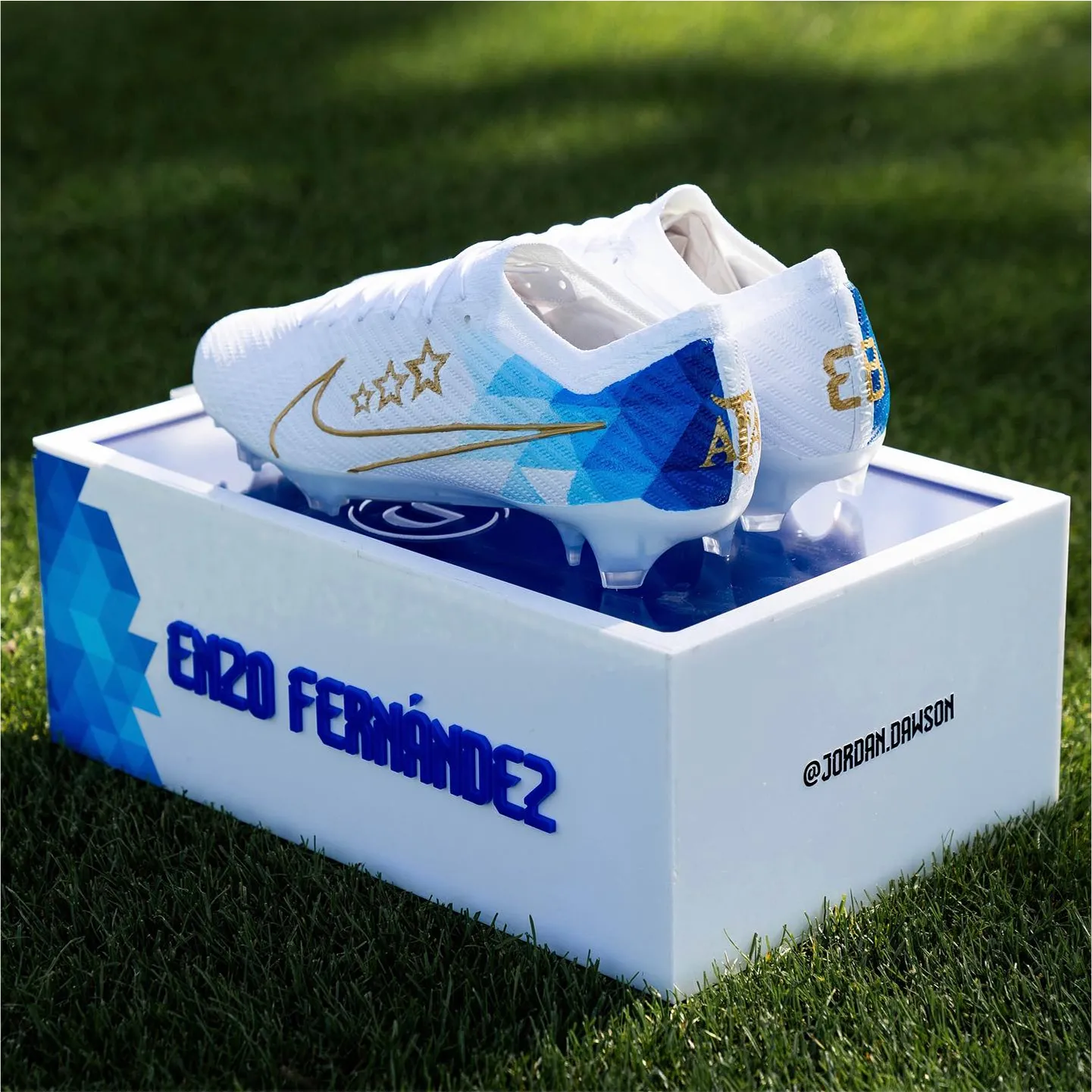 White Nike soccer cleats with blue design sitting on E20 Fernandez box