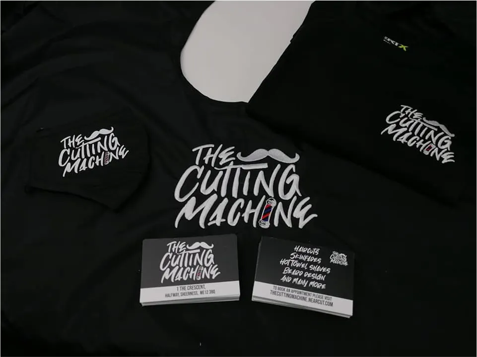 Black shirts and business cards with The Cutting Machine logo