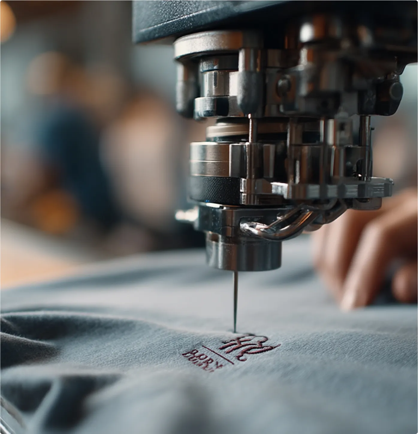 Embroidery machine stitching detailed logo onto gray fabric