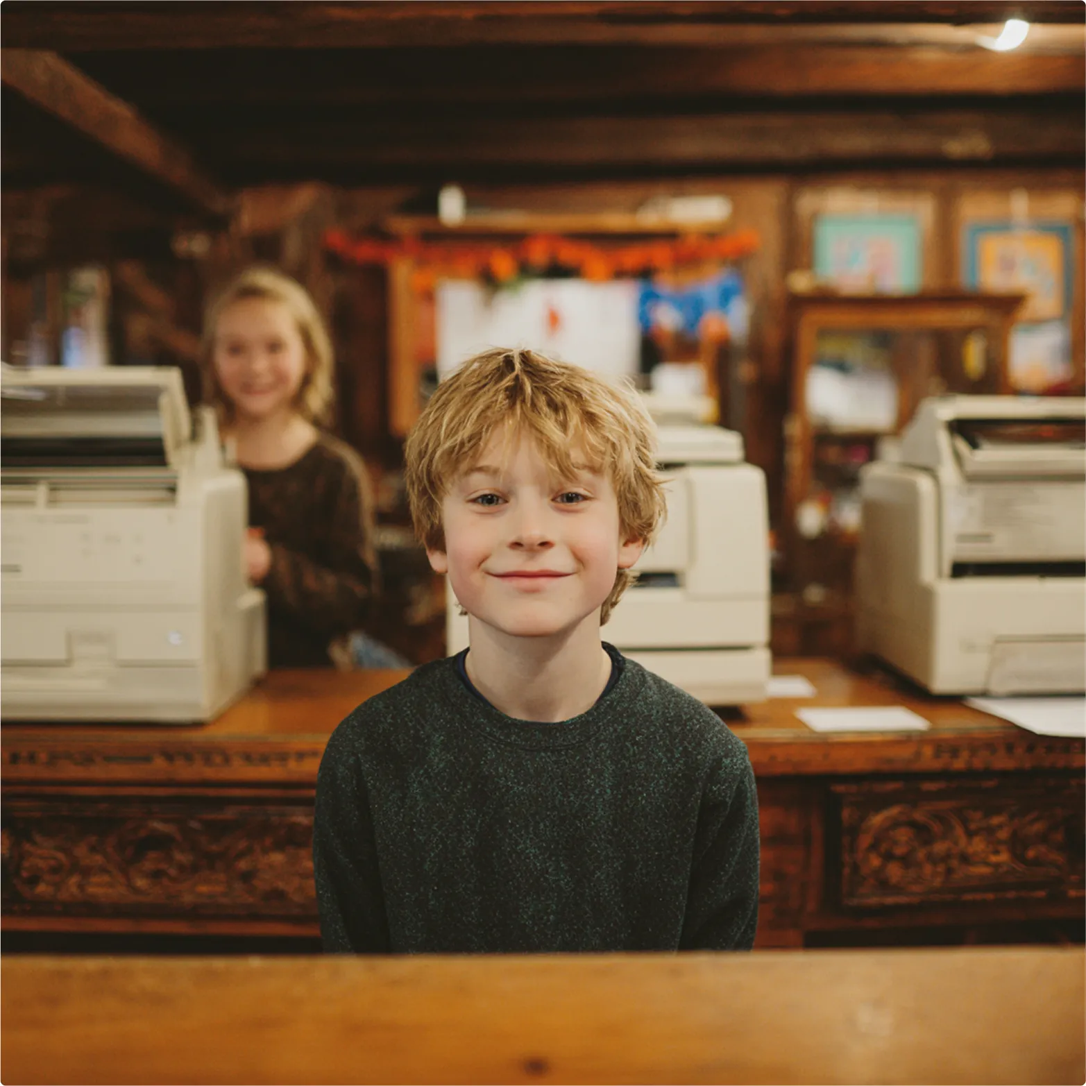 Smiling child sitting at desk with printers and classroom decorations