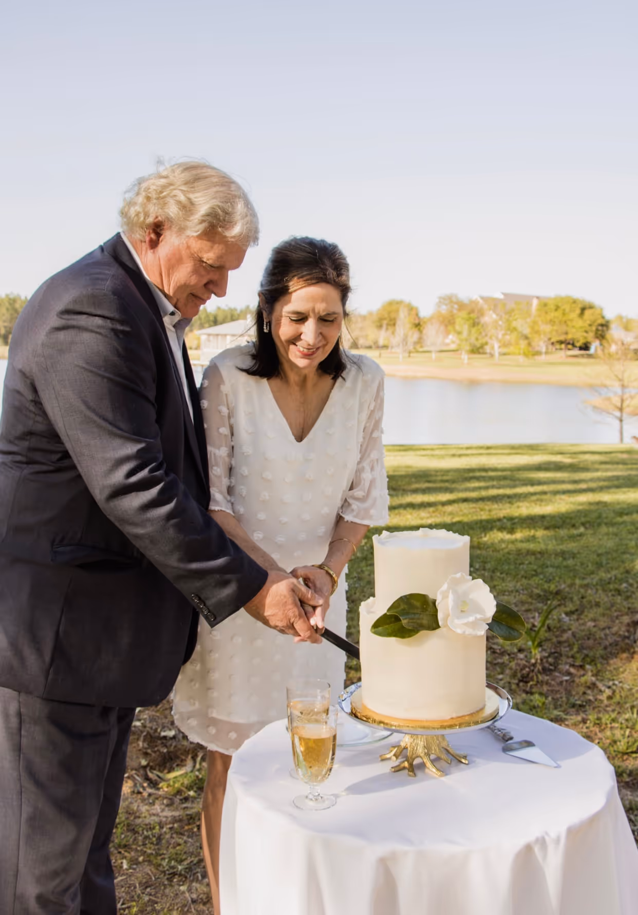 A couple smiles as they cut their wedding cake together.