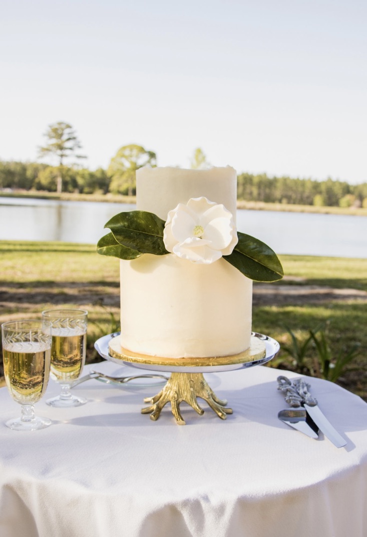 A gorgeous white cake adorned wiht a beautiful flower.