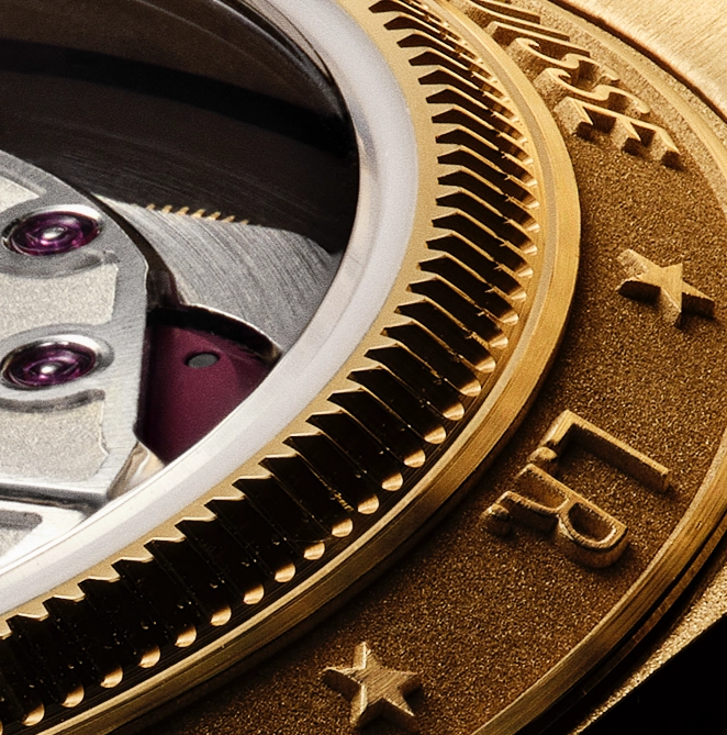 Close-up of a luxury watch's golden bezel featuring textured engravings and part of its mechanical movement with visible jewels.