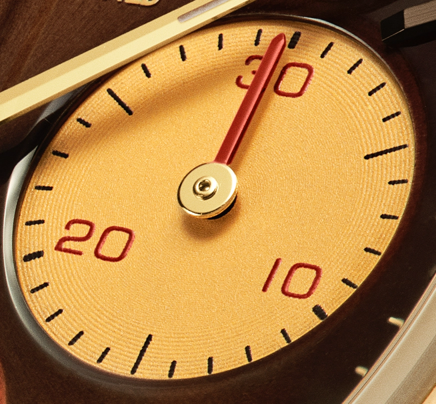 Close-up of a watch subdial with a red hand pointing at 30, featuring gold textured background and red numerals 10, 20, and 30.