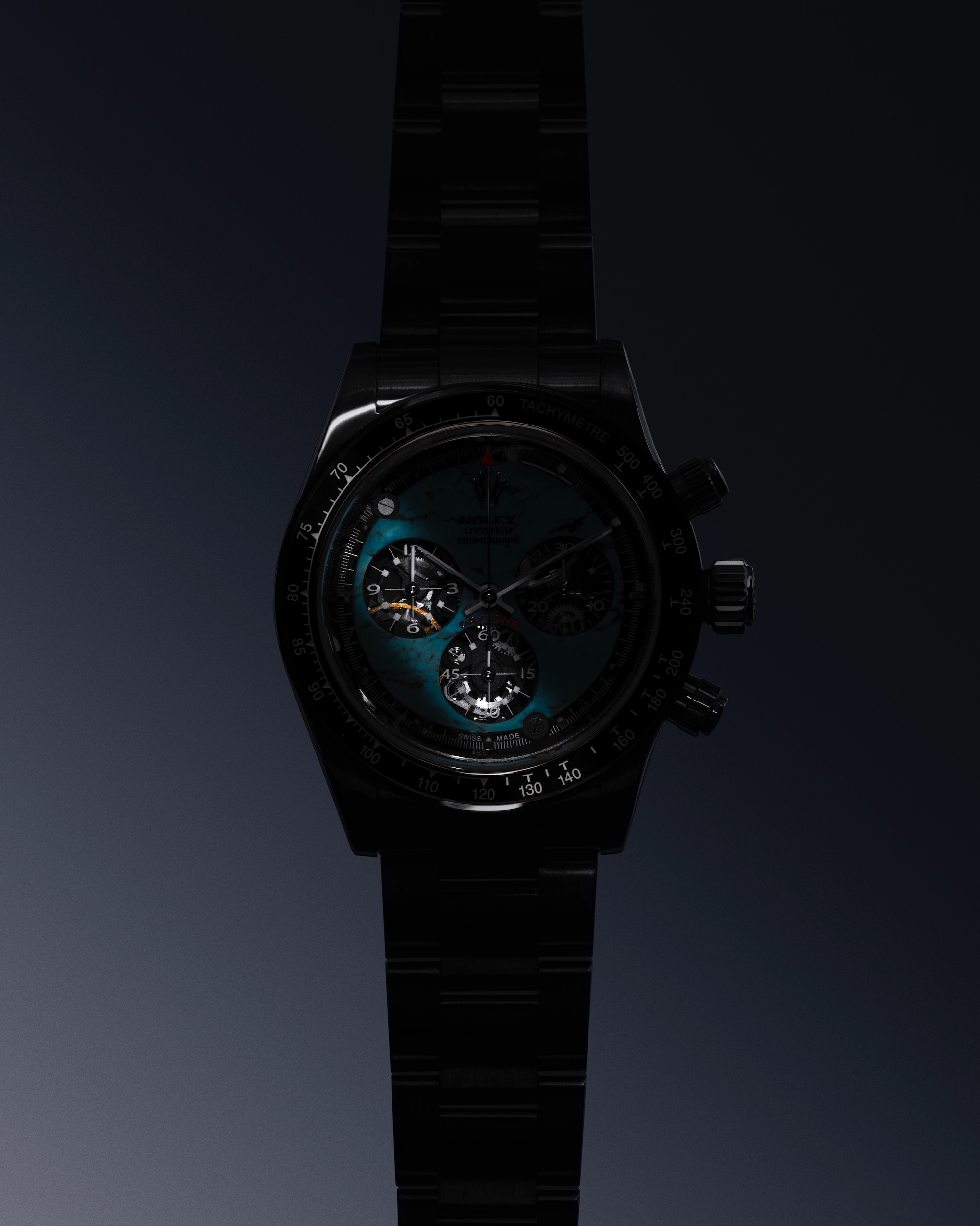 Close-up view of a dark luxury wristwatch with a black metal band and a turquoise dial featuring multiple sub-dials.