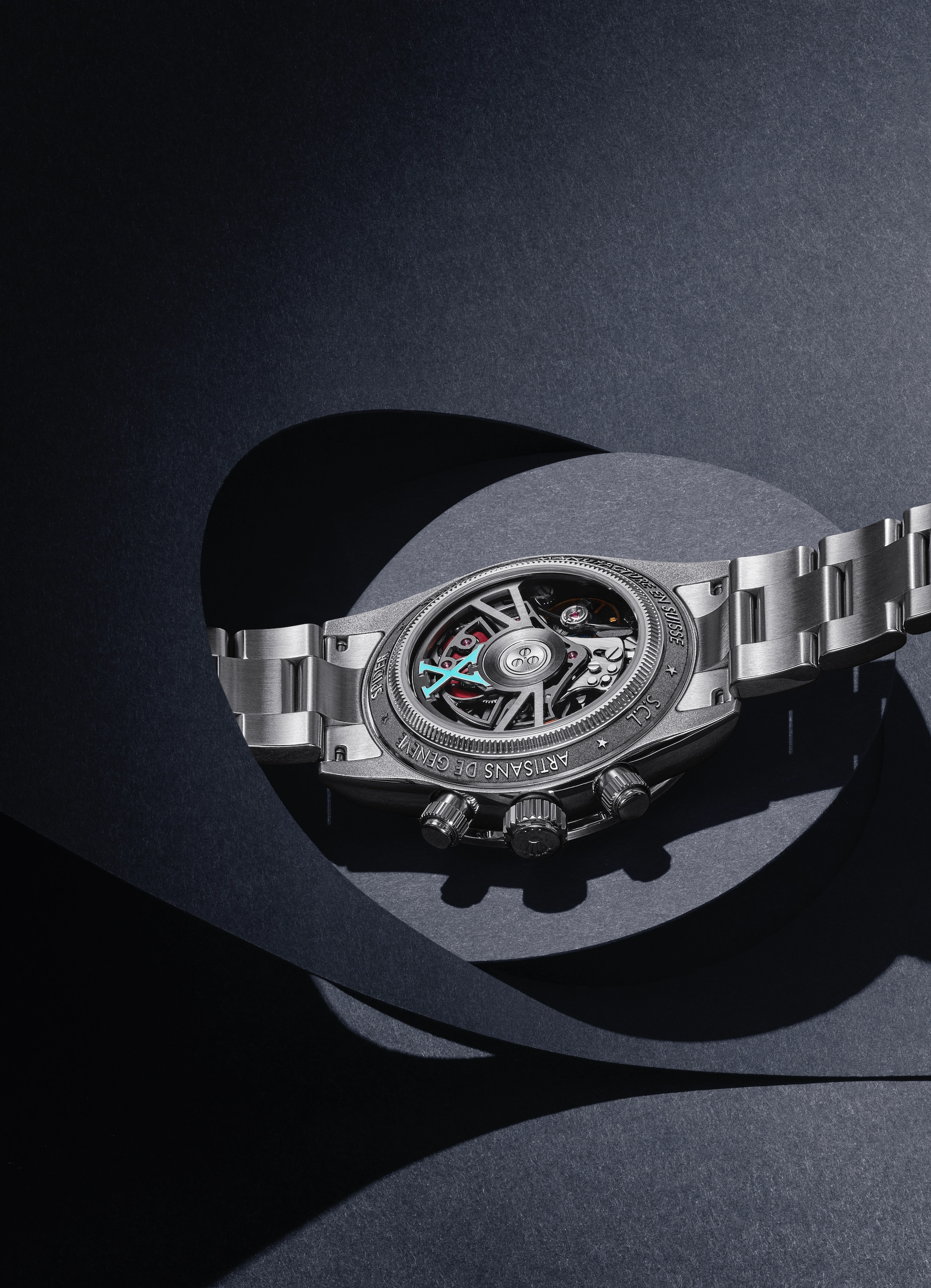 Back view of a stainless steel artisan wristwatch showing intricate mechanical movement with turquoise details.