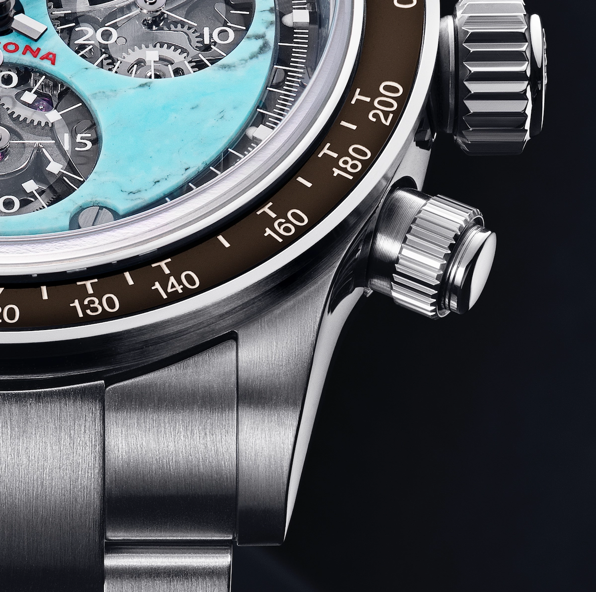 Close-up of a luxury watch with a turquoise subdial, visible gears, and a stainless steel bracelet.