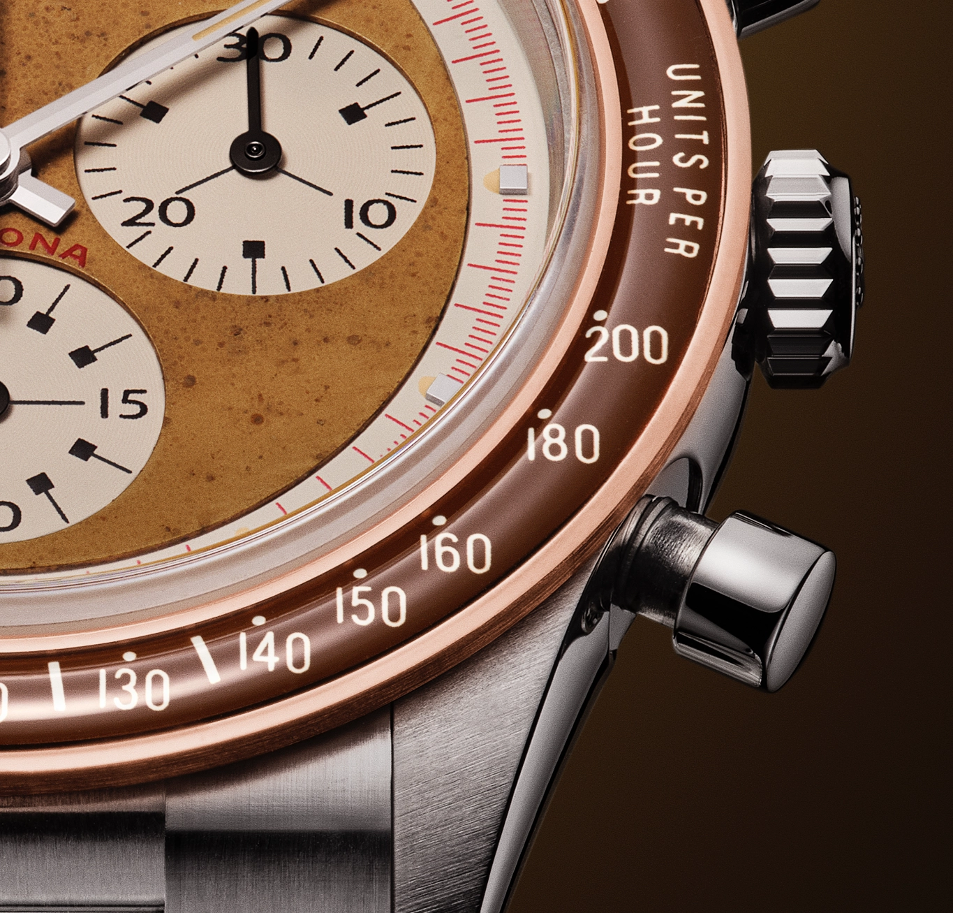 Close-up of a vintage-style chronograph watch face with tachymeter scale and two subdials, featuring a bronze-colored dial and stainless steel case.