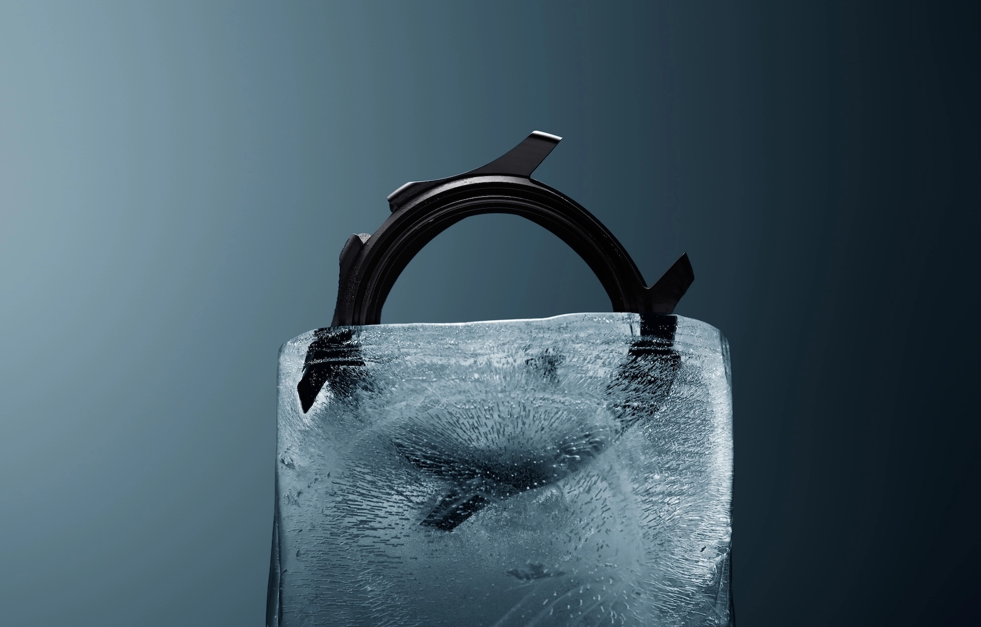 Black watch case partially encased in a clear block of ice against a gradient blue background.