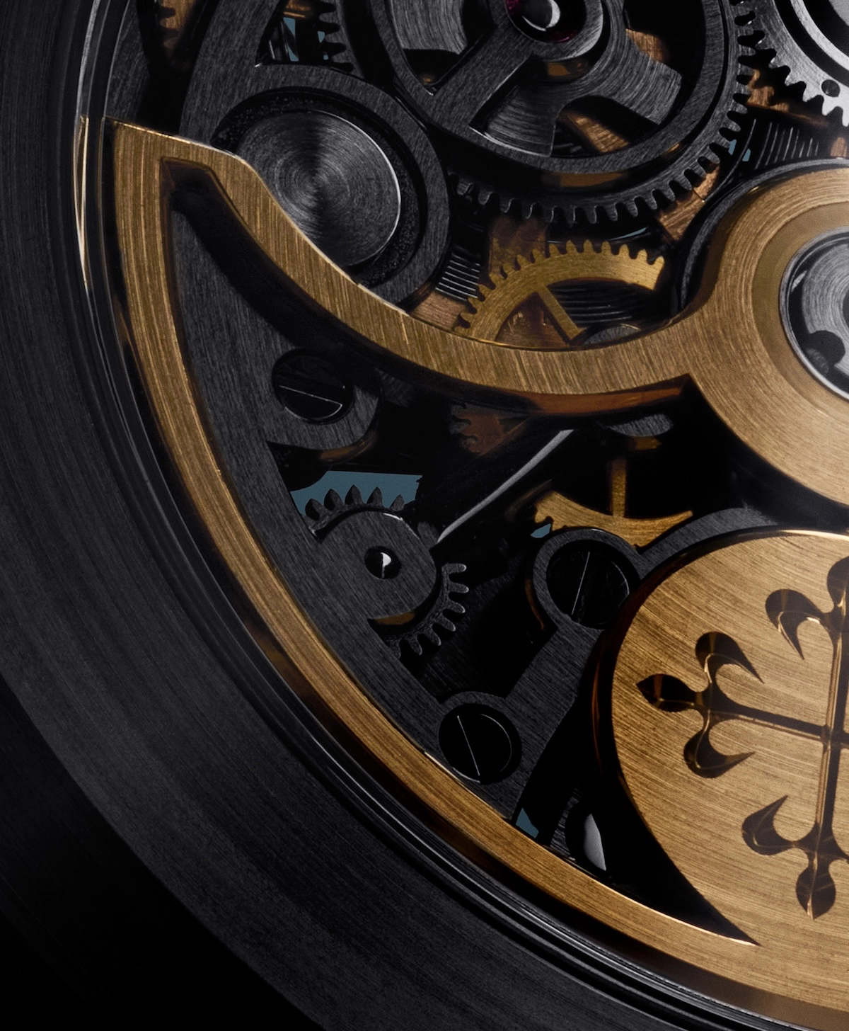 Close-up of black and gold watch gears and a decorative emblem inside a watch mechanism.