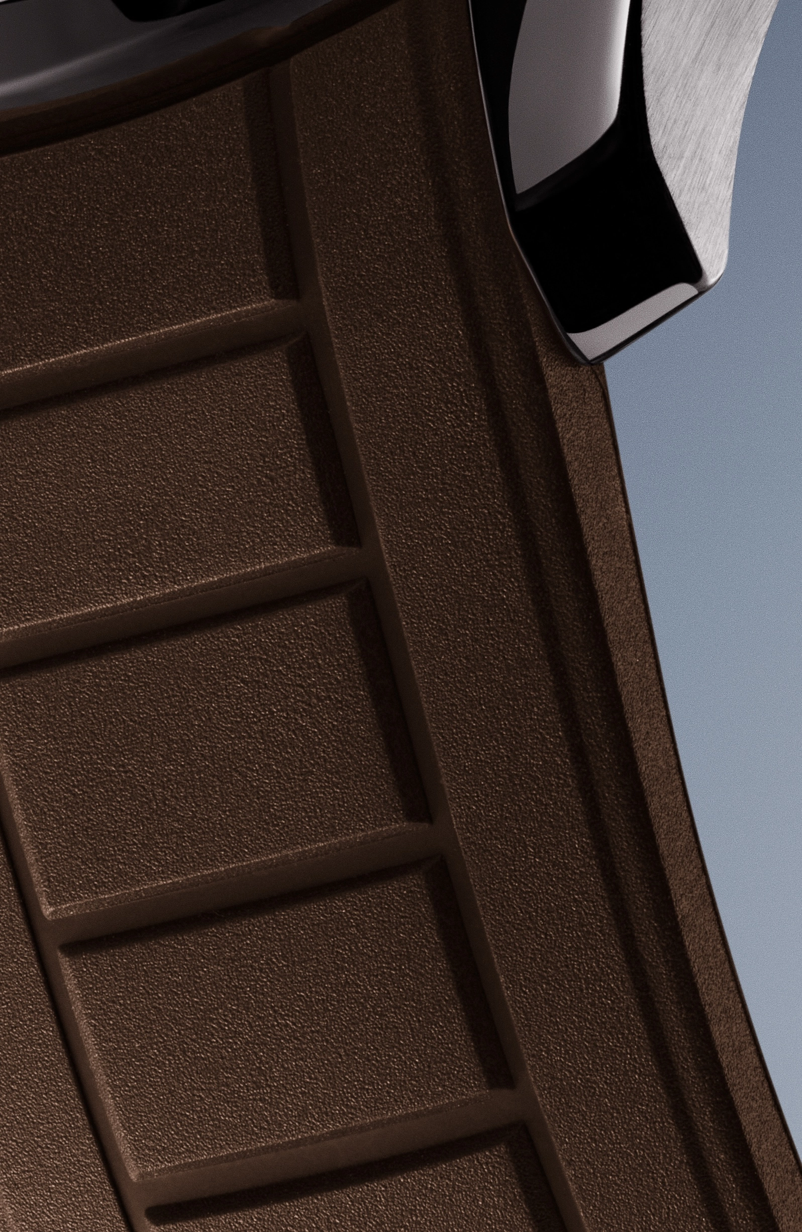 Close-up of textured dark brown rubber watch strap with metal buckle against a gray background.