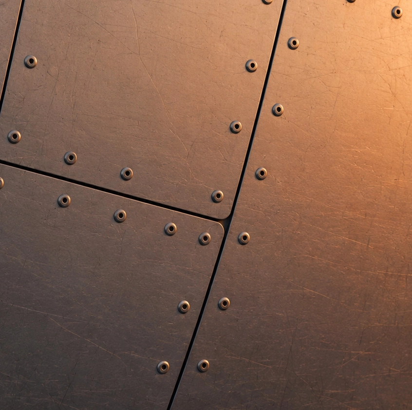 Close-up of metallic panels joined with evenly spaced rivets and lit with warm light.