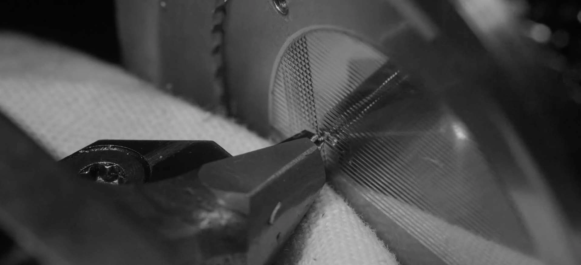 Close-up of a machine engraving fine, detailed guilloché patterns on a metal surface.