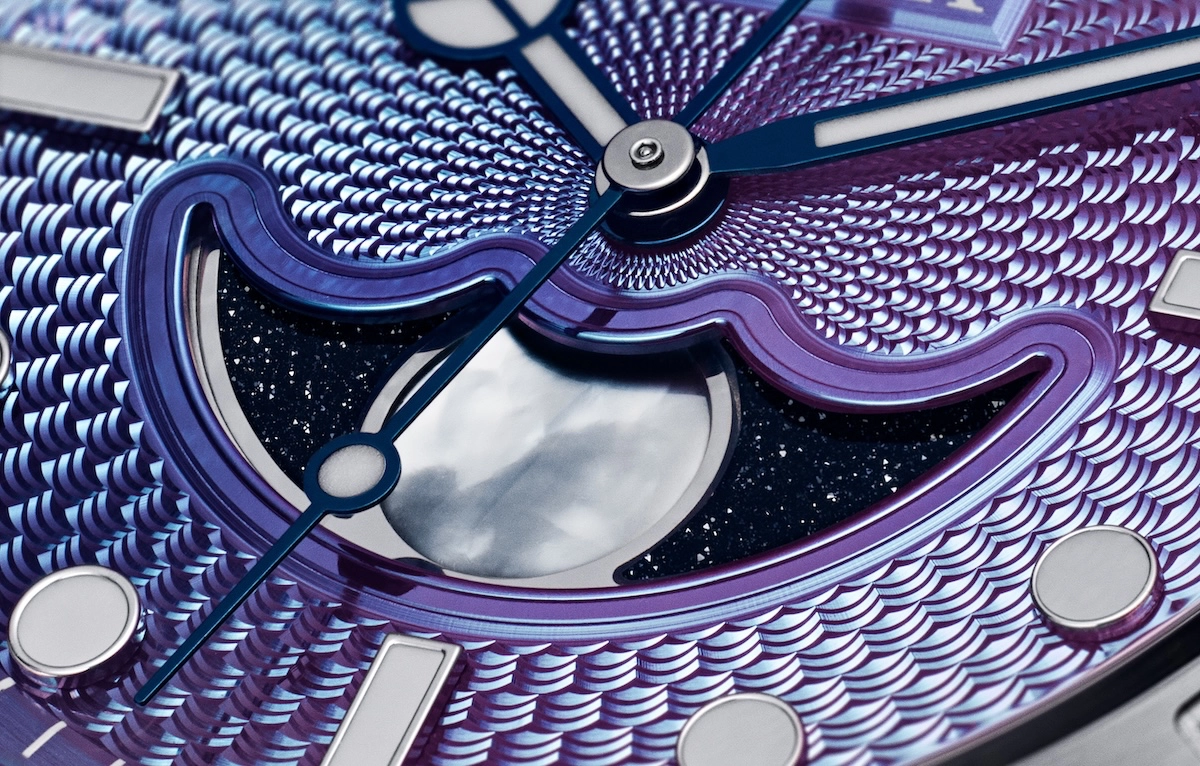 Close-up of a watch dial with a textured purple pattern and a moonphase complication.