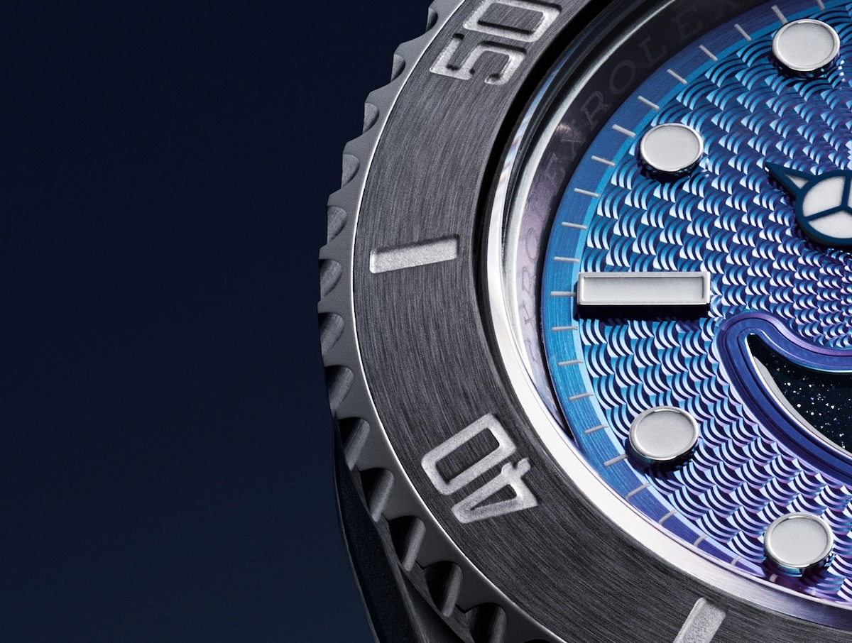 Close-up of a blue textured watch face with silver round hour markers and a brushed metal bezel.