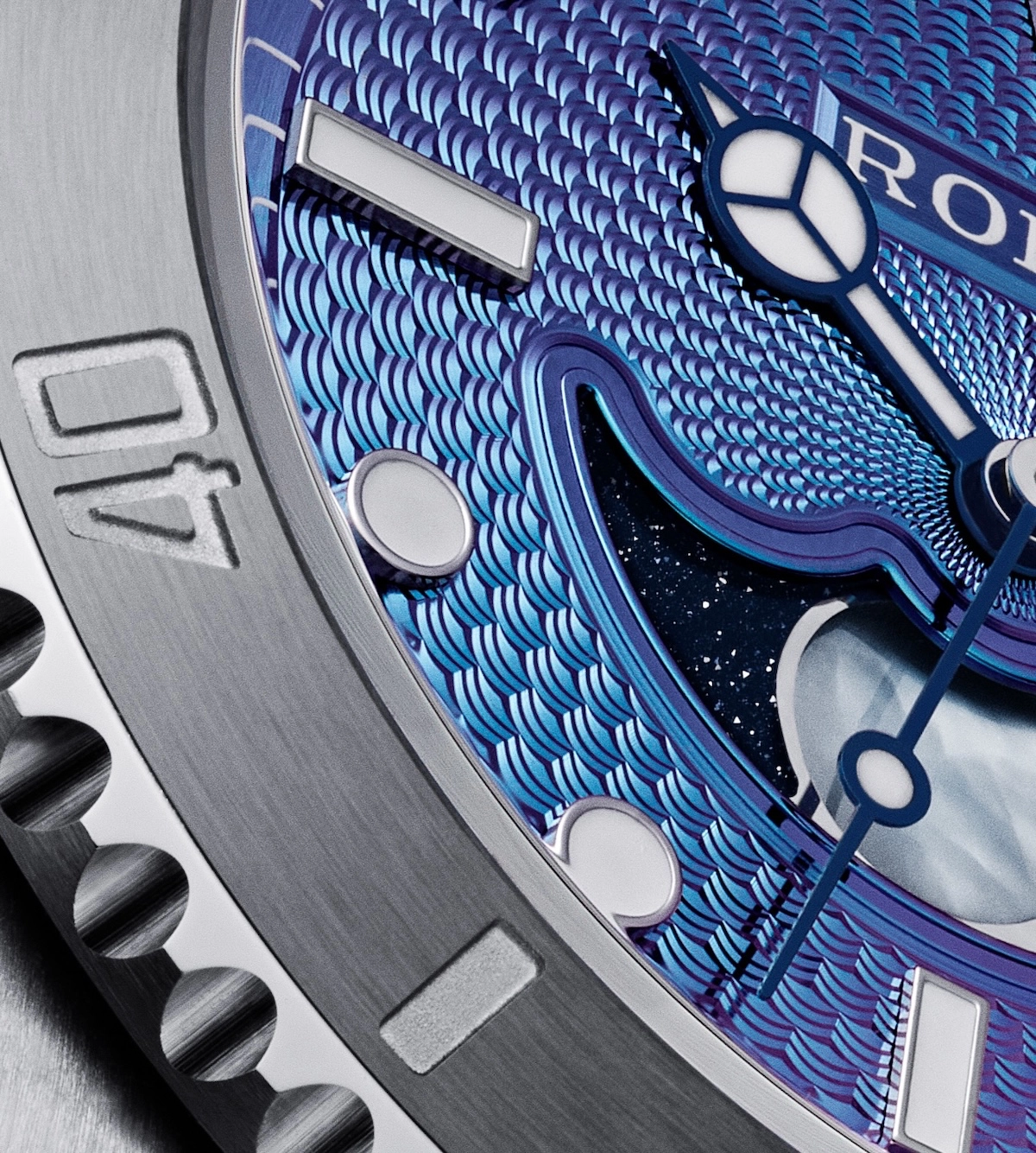 Close-up of a luxury watch with blue guilloché dial, luminous hands, and stainless steel bezel marked 40.
