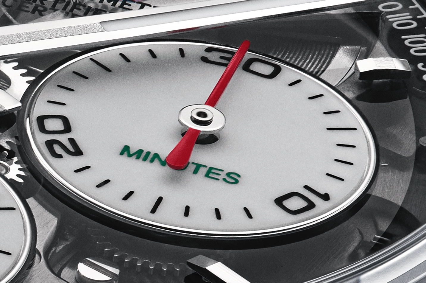 Close-up of a watch dial showing a subdial labeled 'MINUTES' with black numerals 10, 20, and 30, and a red hand pointing at 30.