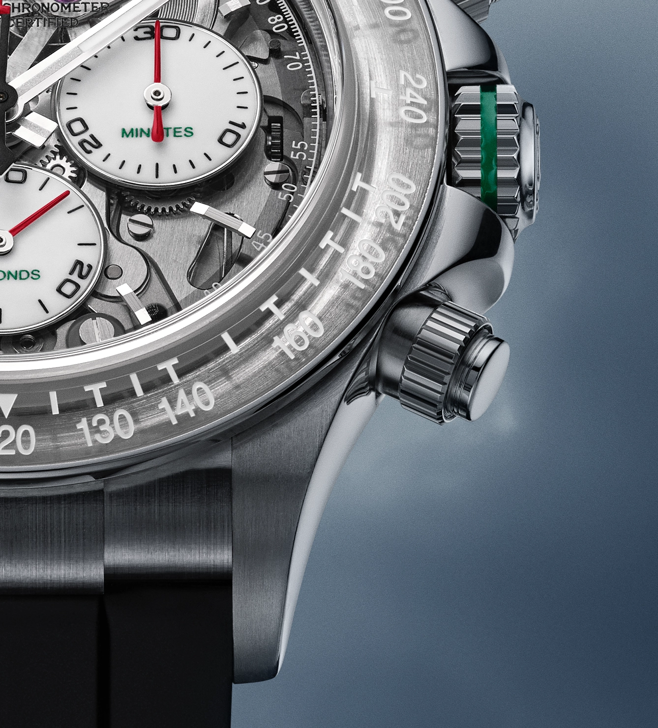 Close-up of a luxury chronometer watch face showing detailed mechanics, two white sub-dials labeled 'MINUTES' and 'SECONDS' with red hands, a tachymeter scale on the bezel, and a polished metal crown with a green accent on the side.