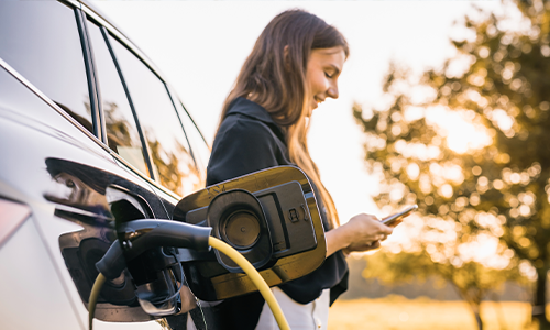 Frau lächelt beim Laden ihres E-Autos mit Solarstrom – nachhaltige Mobilität und erneuerbare Energie