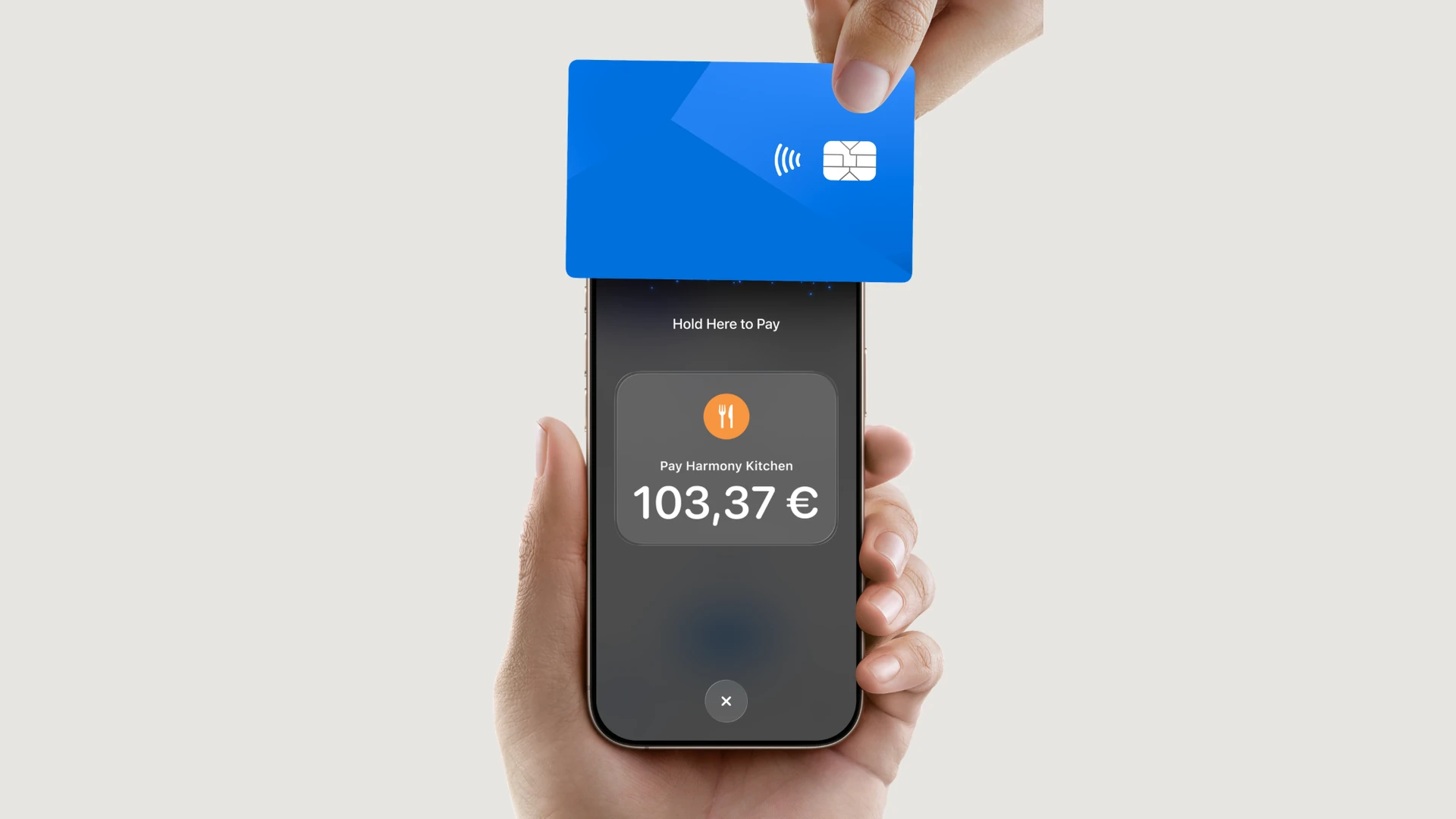 A guest holds a card to a waiter’s iPhone, which shows Hold Here to Pay for Harmony Kitchen, 103,37 €