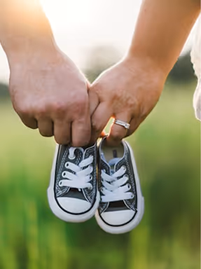 couple with a pair of child's shoes in their hands