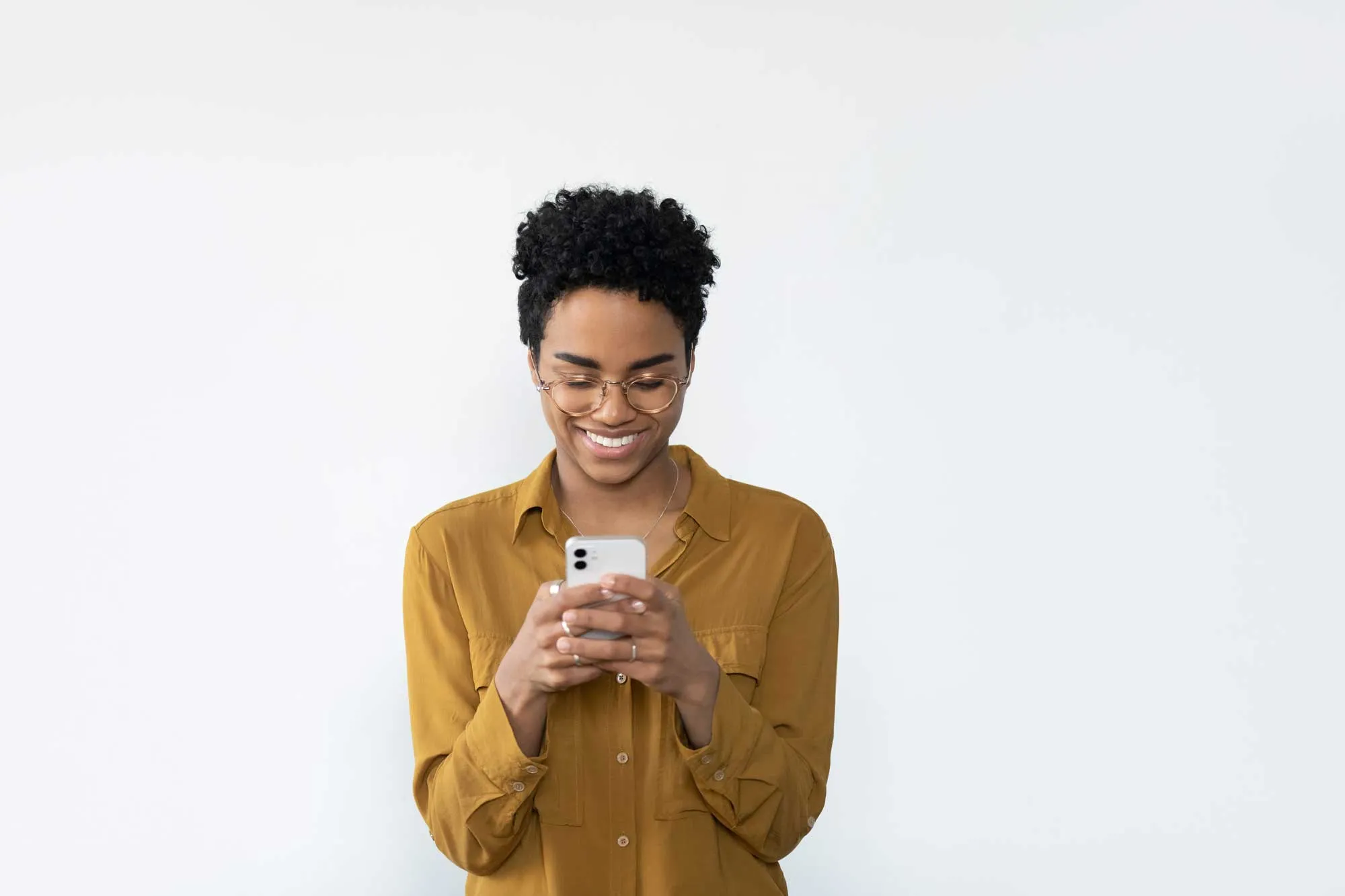 A woman in a yellow shirt is looking at her cell phone.
