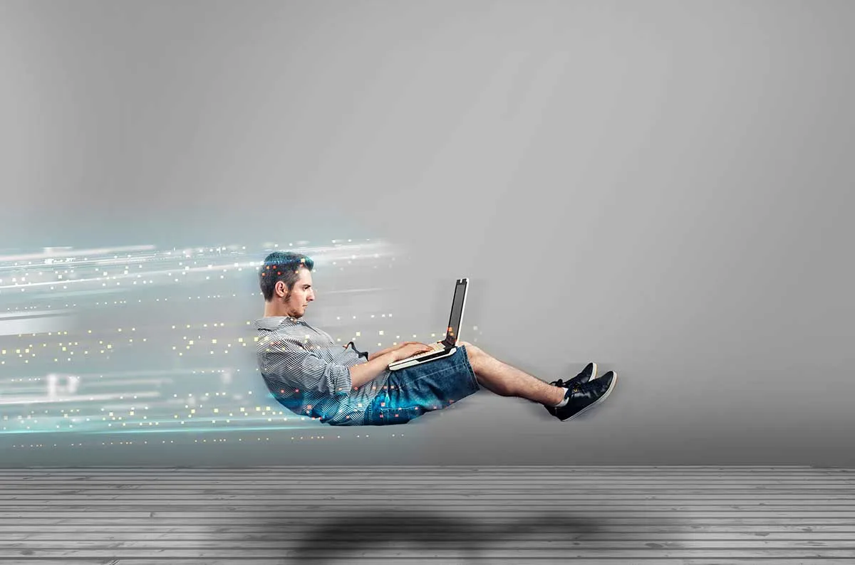 A man sitting on the floor using a laptop computer.