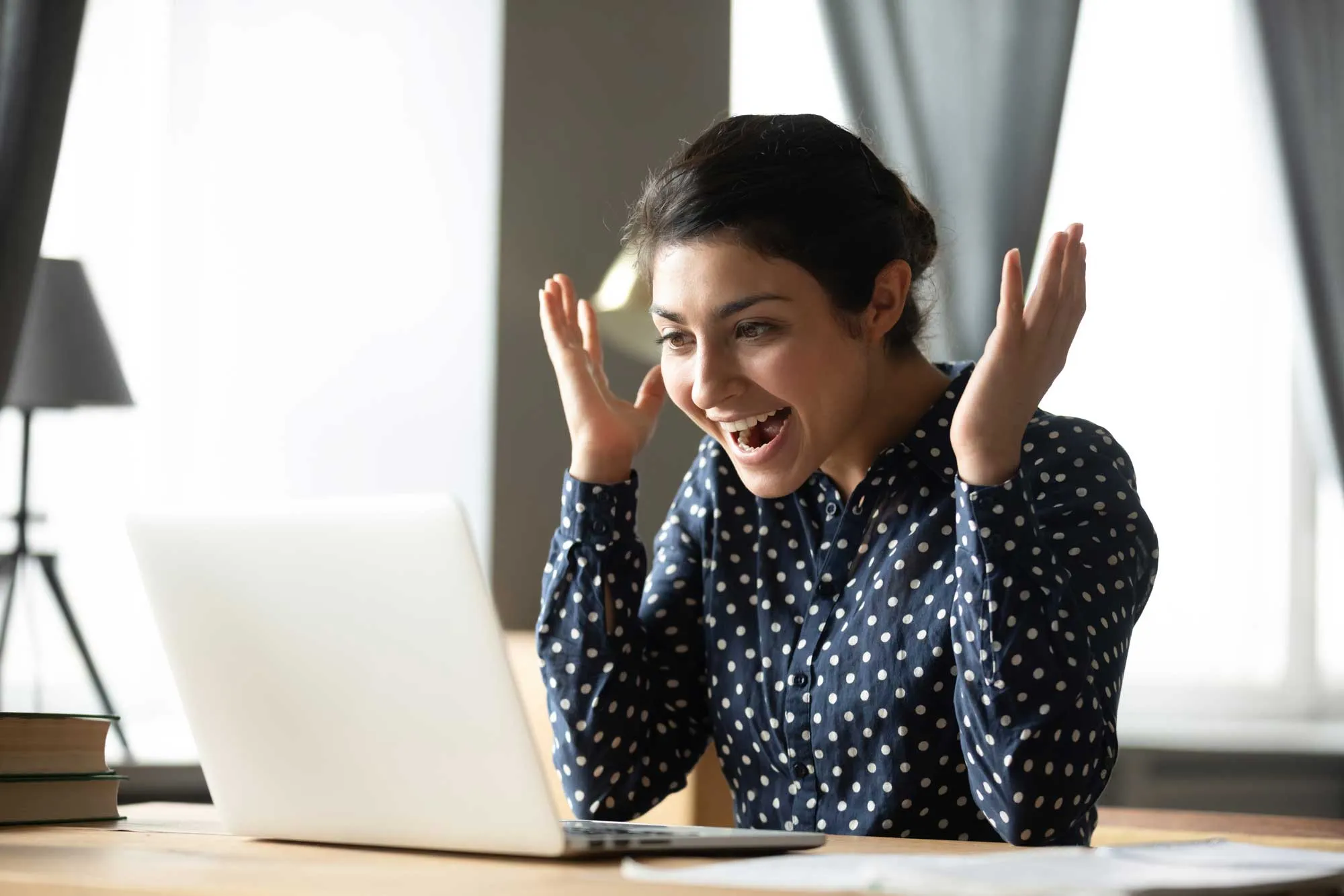 A woman sitting at a table with a laptop in front of her.