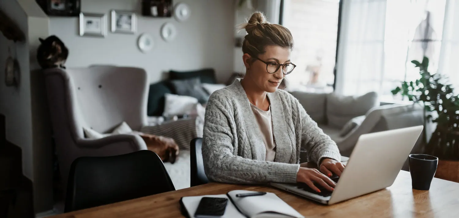 A woman sitting at a table using a laptop computer.