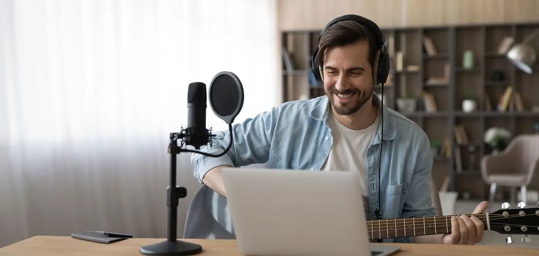 A man sitting in front of a laptop with headphones on.