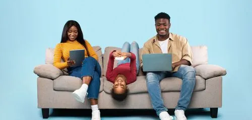 A man and a woman sitting on a couch with laptops.