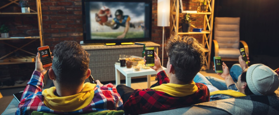 Two young boys sitting on a couch watching tv.