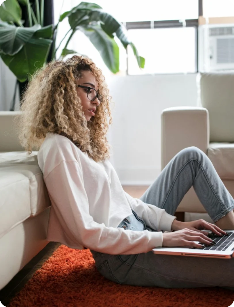 A woman sitting on the floor using a laptop computer.