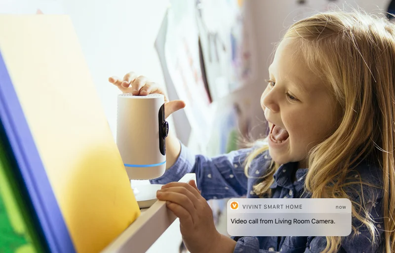 A little girl holding a smart device and laughing.