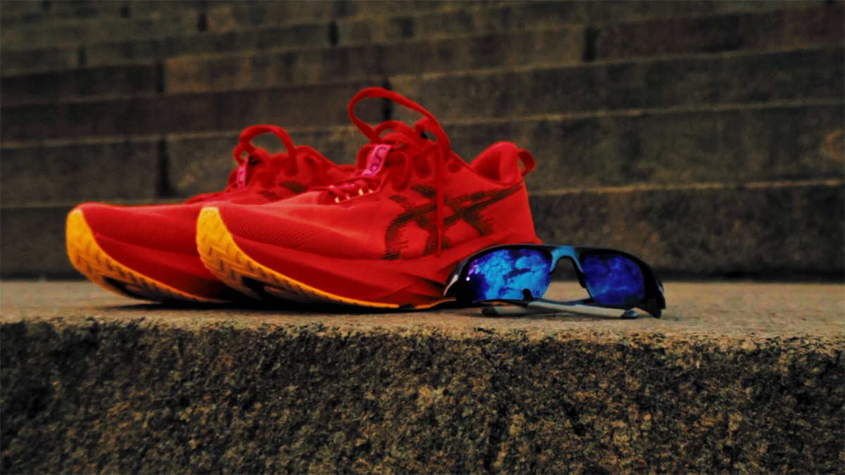Red running shoes and y2k glasses sitting on top of steps.