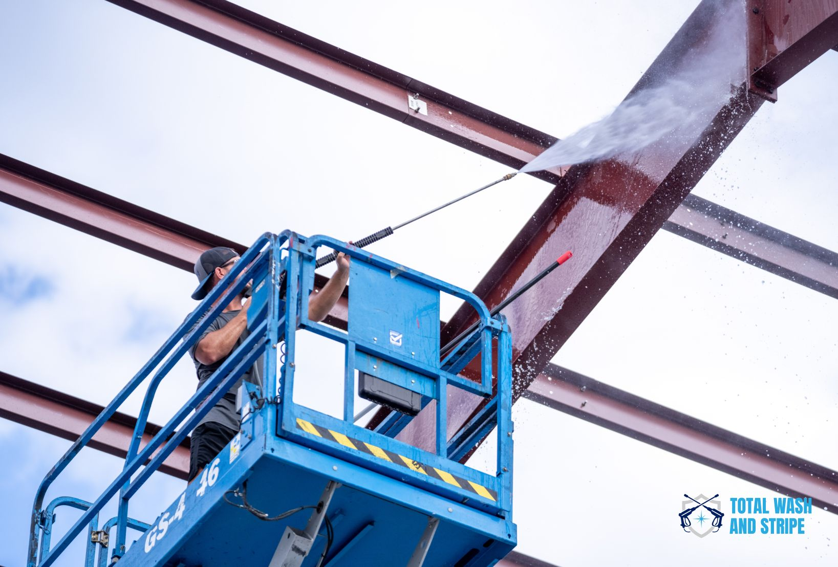 Pressure washing structural steel beams from a boom lift