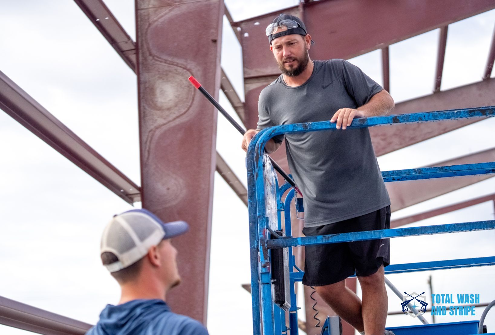 Technician cleaning a structural steel column from an aerial lift