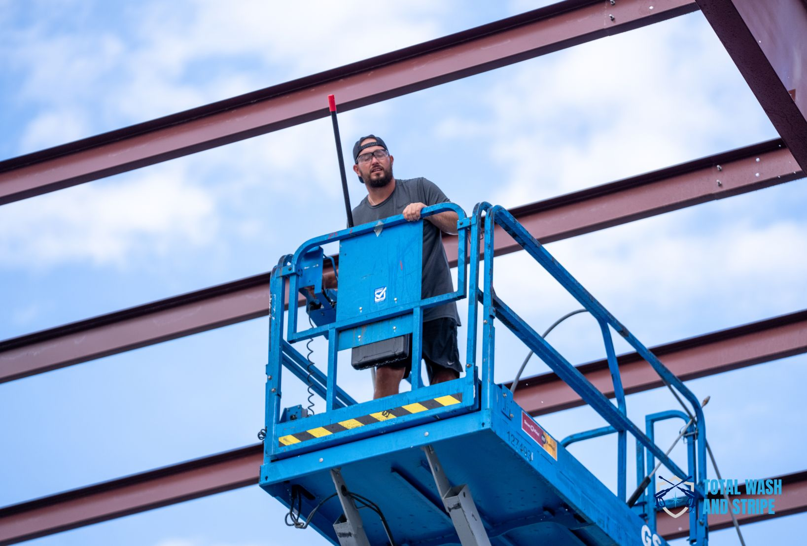 Technician on a boom lift cleaning structural steel beams