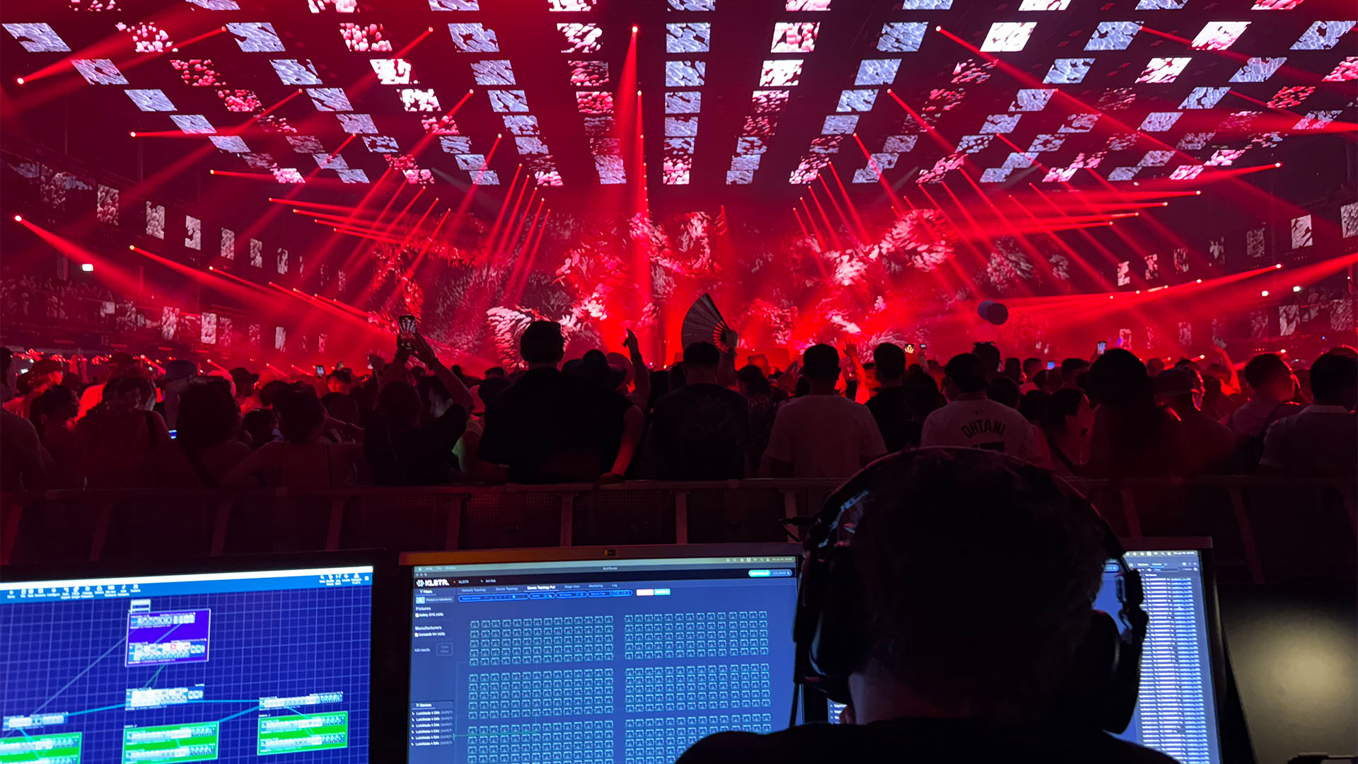 Production control consoles overlooking a red-lit stage with suspended rectangular panels