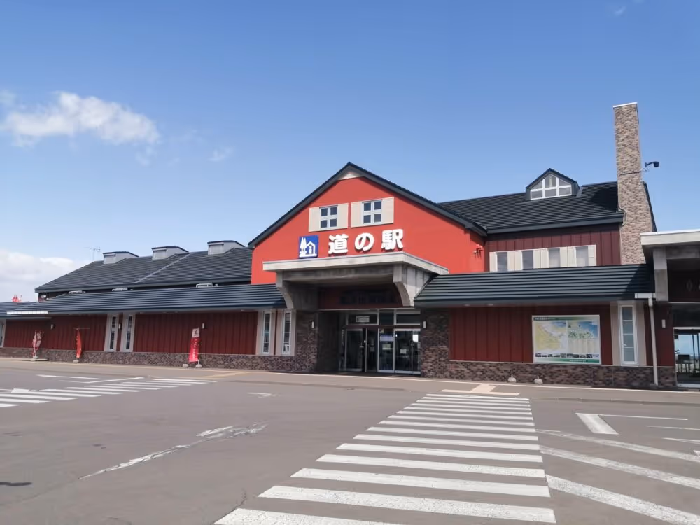 Red building with dark roof and Japanese signage under a partly cloudy blue sky.