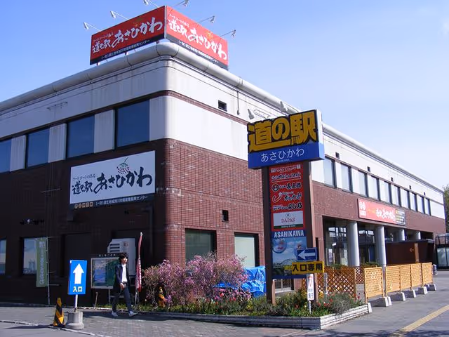 Exterior view of a brown and white roadside station building with Japanese signage and a person walking near the entrance.