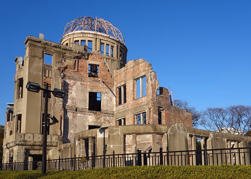 Ruins of the Atomic Bomb Dome in Hiroshima with clear blue sky and surrounding greenery.